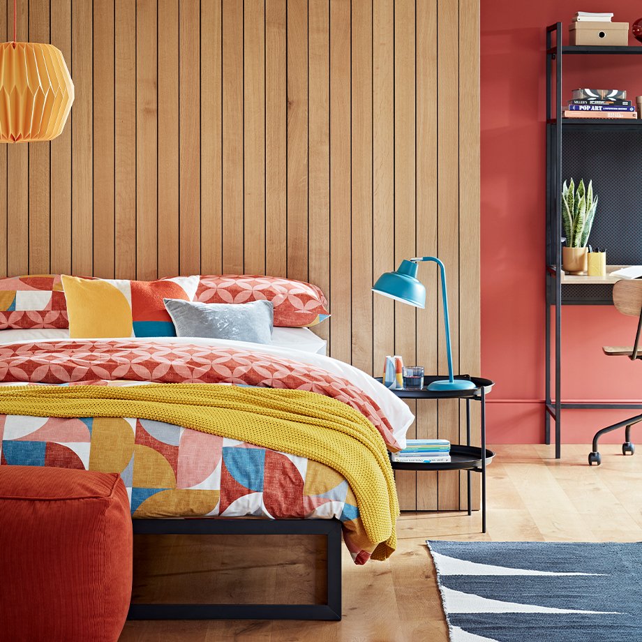 Burnt orange geometric bedding on industrial black bed frame.